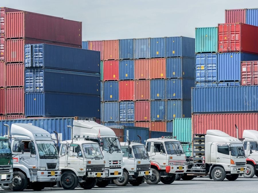 Fleet of trucks beside stacked containers